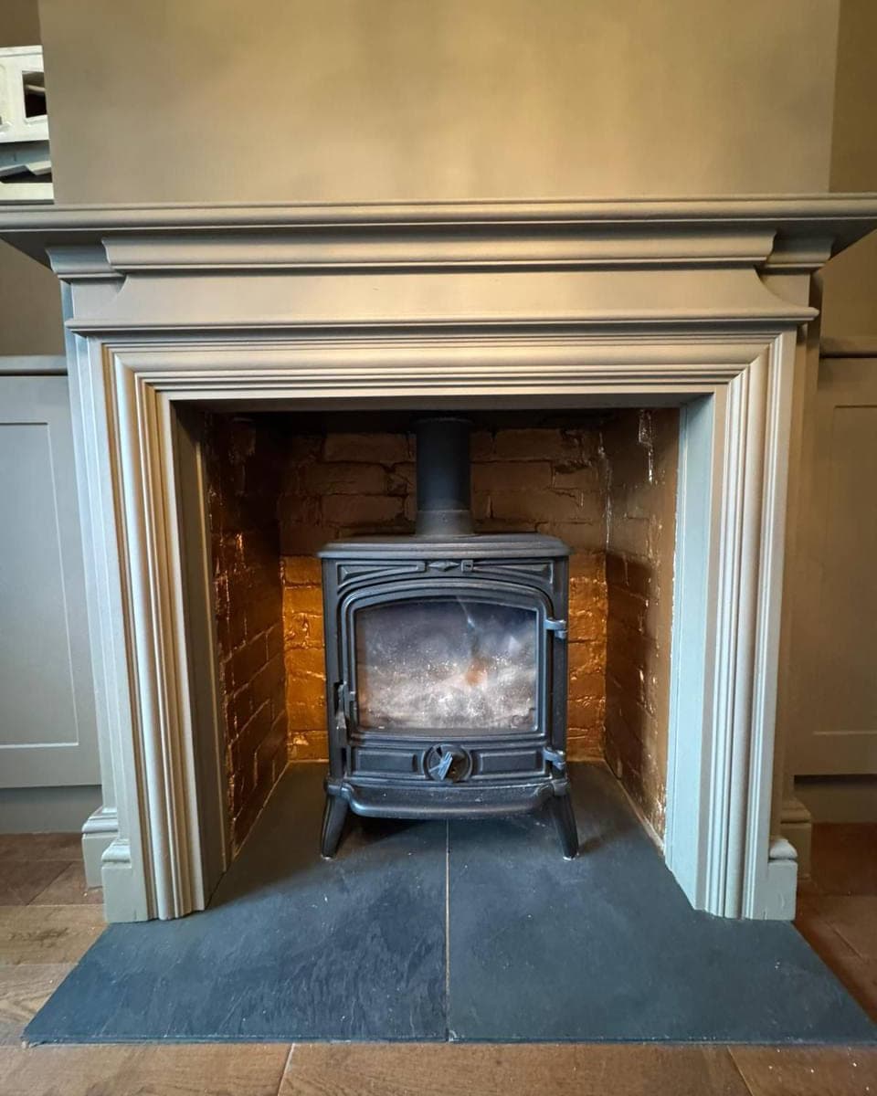 A painted fireplace surround and mantel, cut in around the hearth and the cabinetry either side