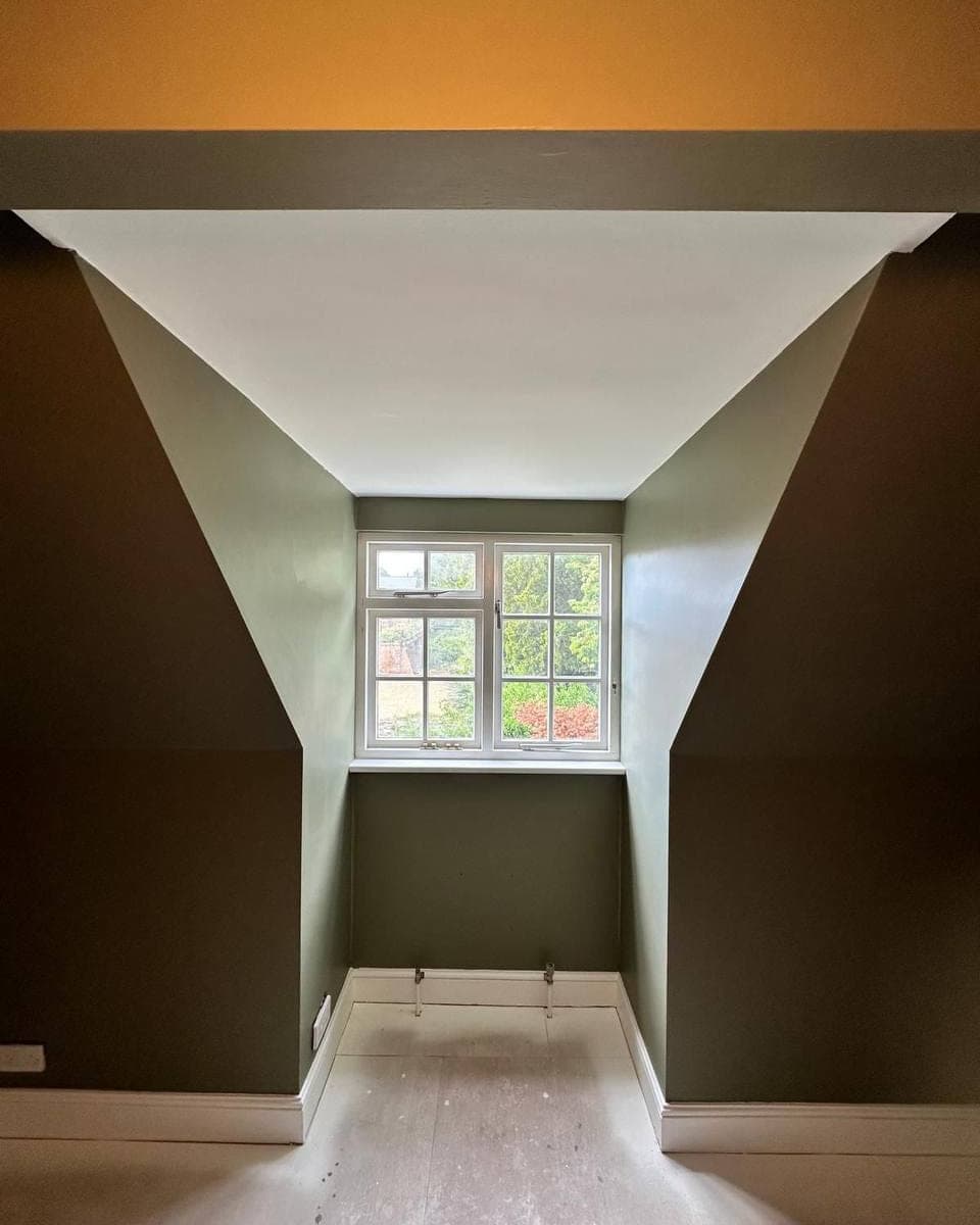 A room part way through: walls and ceiling finished in olive and white, floor still to go back down