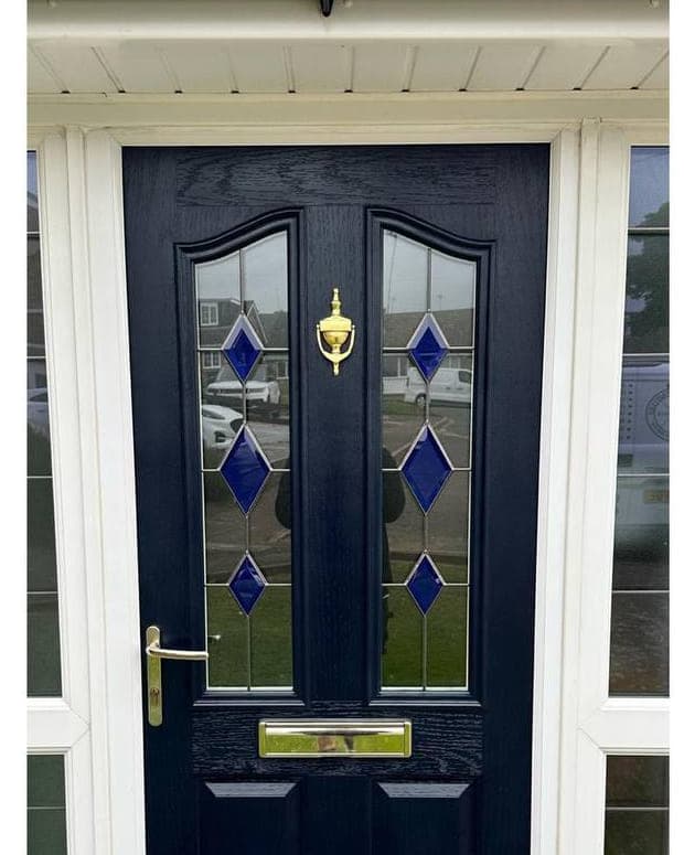 A front door sprayed deep navy, with the brass knocker and letterplate against the new finish