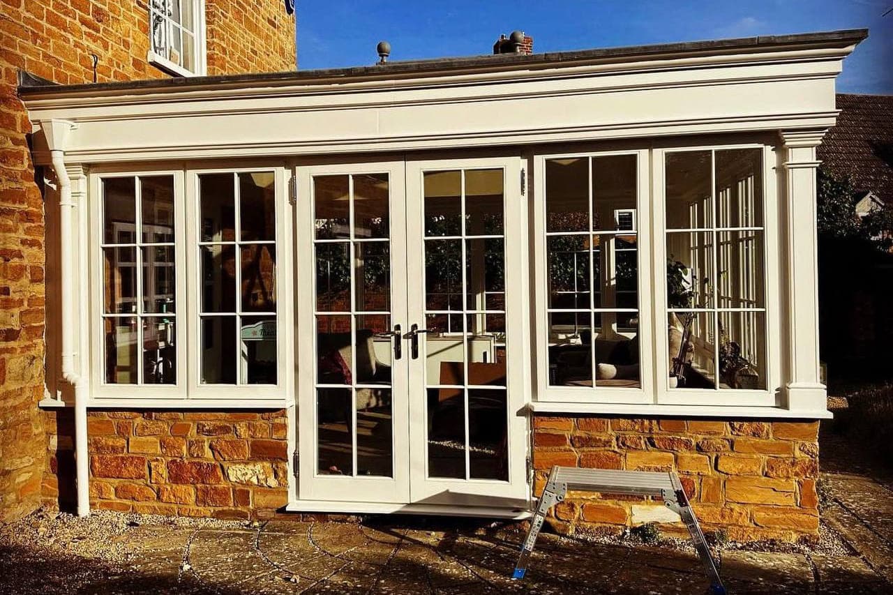 A glazed garden room with every frame, mullion and cornice sprayed in cream